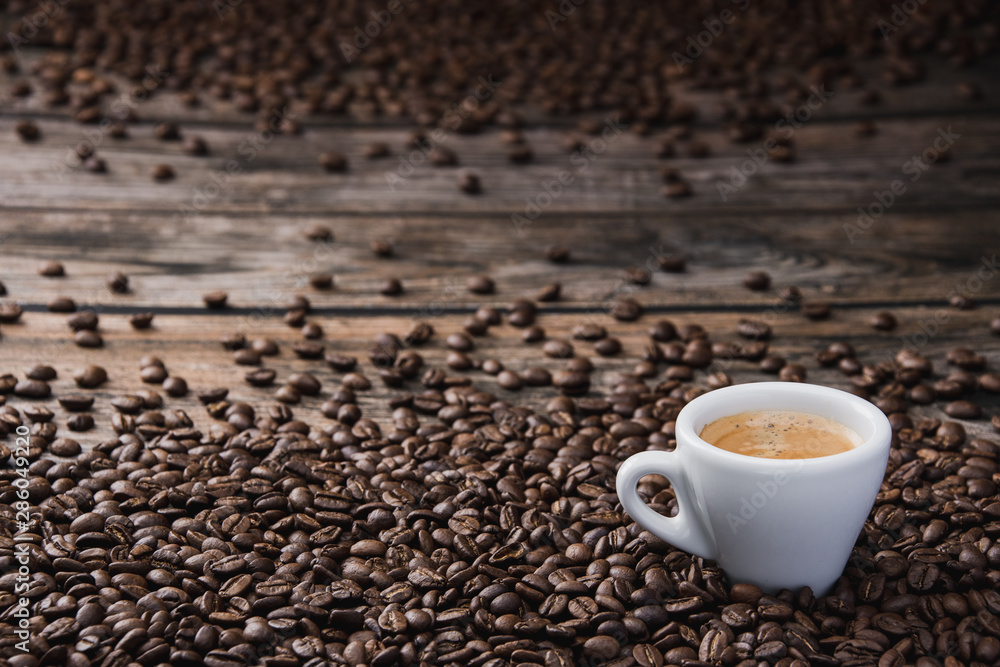 Fototapeta premium White cup of coffee espresso with beans on brown wooden table