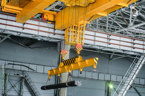 Yellow overhead crane carries cargo in engineering plant shop. Jib crab trolley with hooks and linear traverse. photo