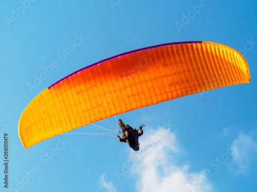 Paraglider is flying in the blue sky.