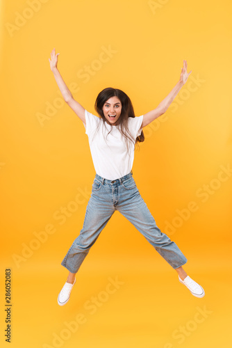 Full length image of happy brunette woman with long hair smiling while rejoicing and dancing © Drobot Dean