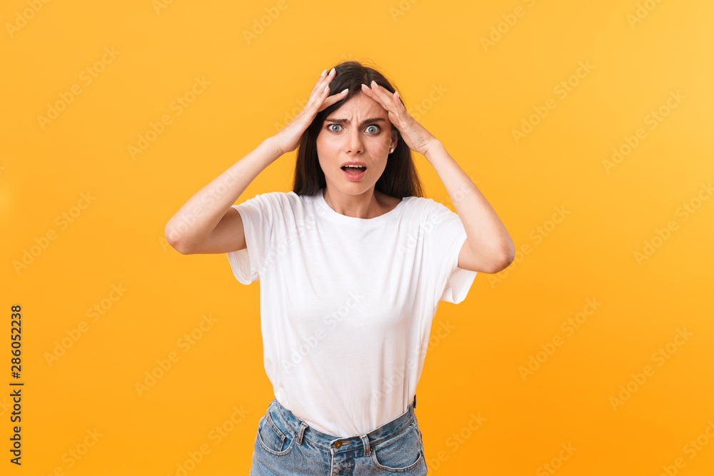 Image of upset confused brunette woman wearing basic clothes frowning and grabbing head Image of upset confused brunette woman wearing basic clothes frowning and grabbing head