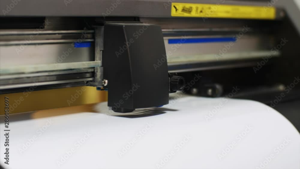 Modern computerized equipment in printing house. Industrial plotter machine cutting self-adhesive film according to the specified parameters in typography. Publishing business and industry. Modern computerized equipment in printing house. Industrial plotter machine cutting self-adhesive film according to the specified parameters in typography. Publishing business and industry.