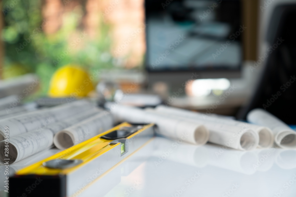 Contractor concept. Yellow hardhat, libella and plans on the white table. Contractor concept. Yellow hardhat, libella and plans on the white table.