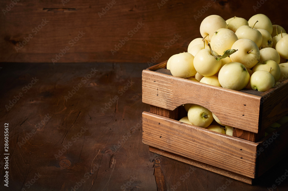 Freshly harvested small apples in boxon wooden background