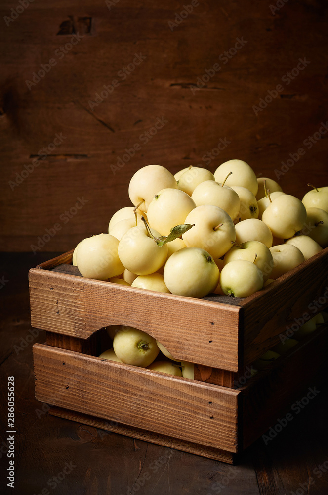 Freshly harvested small apples in boxon wooden background