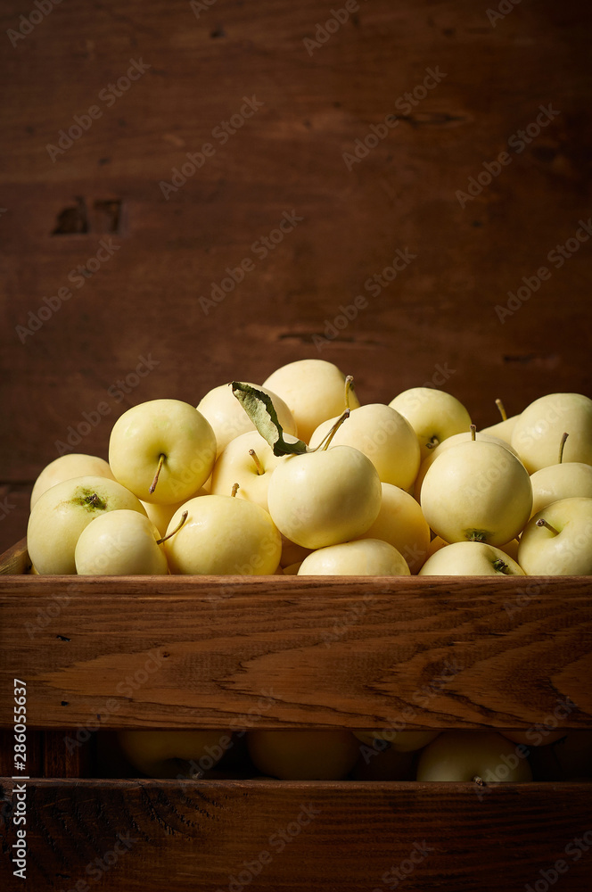 Freshly harvested small apples in boxon wooden background