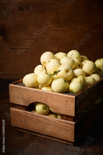 Freshly harvested small apples in boxon wooden background photo