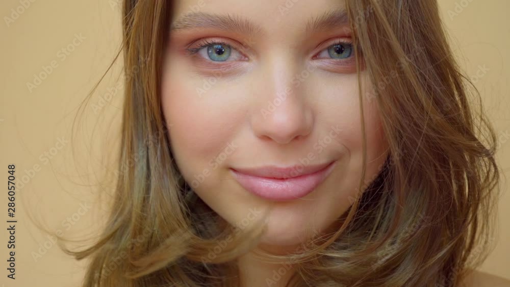 closeup portrait of young wooman posing to a camera with blowed out hair on grey closeup portrait of young wooman posing to a camera with blowed out hair on grey