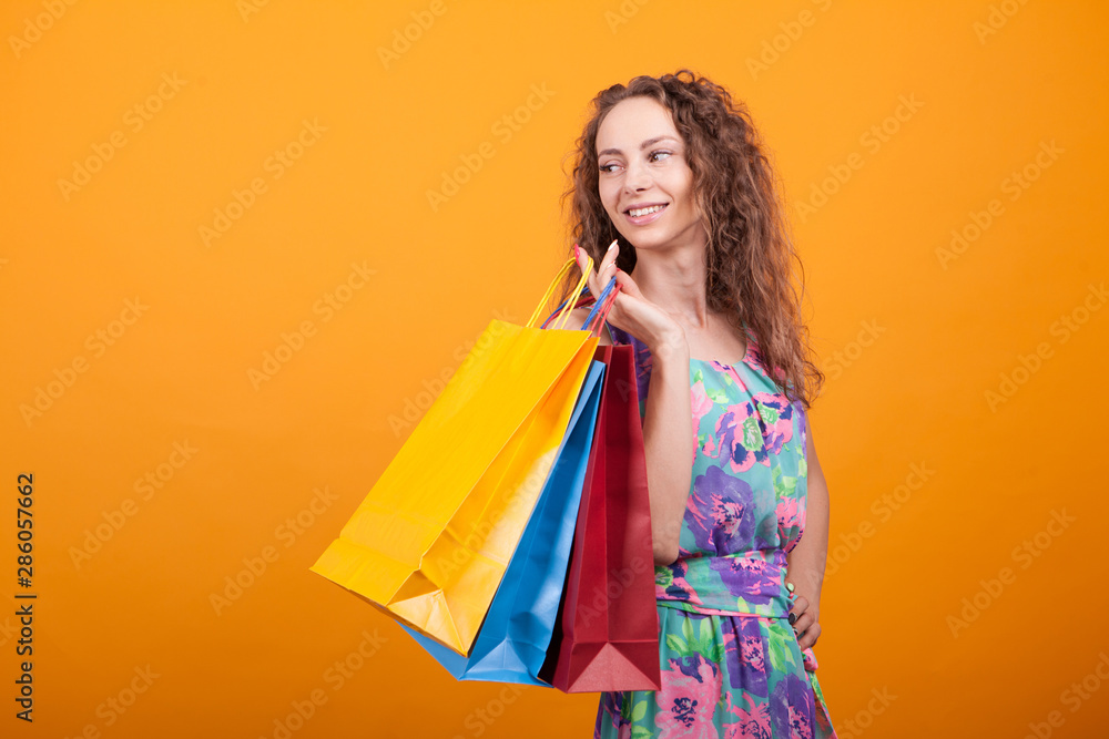 Curly woman smiling and holding multiple shopping bags Curly woman smiling and holding multiple shopping bags