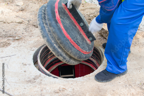 the worker’s hands in white gloves open the collector cover for electrical communications