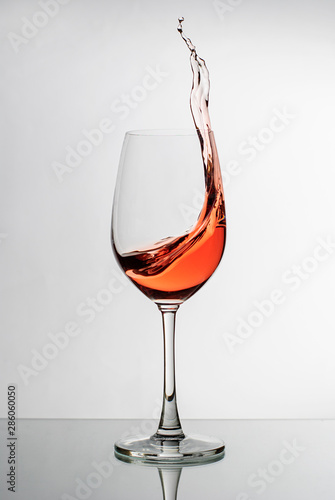Pink wine splashing up the side of a wineglass