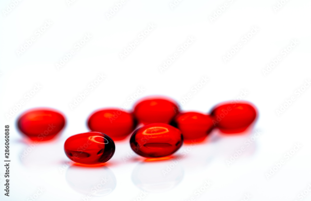 Red soft gel capsule pills isolated on white background. Pile of red soft gelatin capsule. Vitamins and dietary supplements concept. Pharmaceutical industry. Pharmacy drug store. Health care products. Red soft gel capsule pills isolated on white background. Pile of red soft gelatin capsule. Vitamins and dietary supplements concept. Pharmaceutical industry. Pharmacy drug store. Health care products.