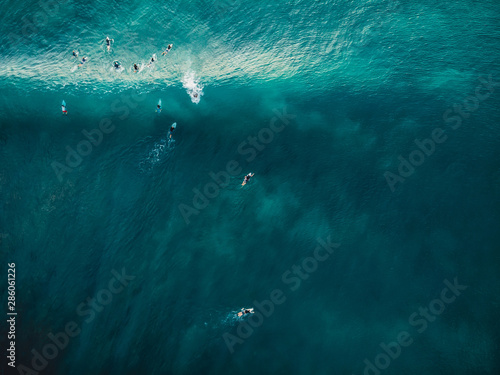 Aerial view with surfers and barrel wave in tropical blue ocean. Top view