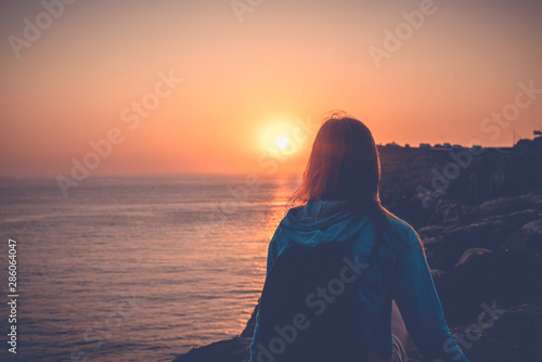 Girl watching the sunset on the ocean