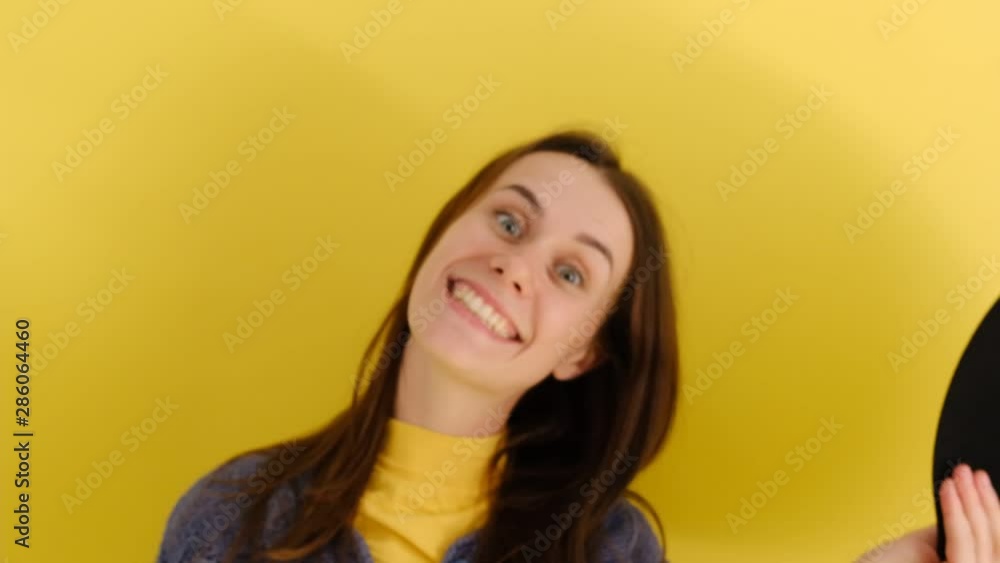 Funny beautiful female in hat, smiles gladfully, sticking out her tongue at camera, isolated on yelow background. Caucasian woman poses indoor Funny beautiful female in hat, smiles gladfully, sticking out her tongue at camera, isolated on yelow background. Caucasian woman poses indoor