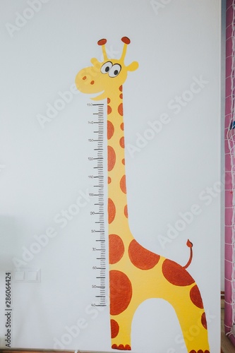 Obraz na płótnie Funny giraffe at a daycare to measure children's height