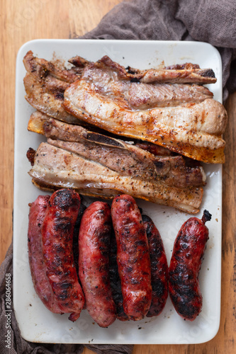 grilled meat and sausages on dish on wooden background