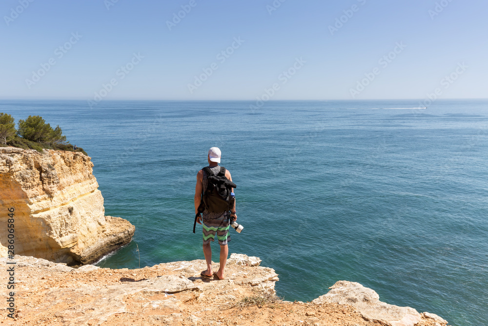 Mann mit Kamera steht auf den Klippen am Meer
