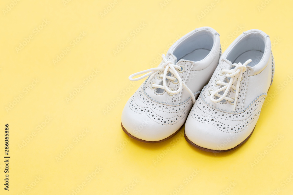 Naklejka premium white baby shoes on yellow background