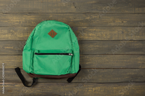 Obraz na plátně Back to school concept - green backpack on wooden backgroung,
