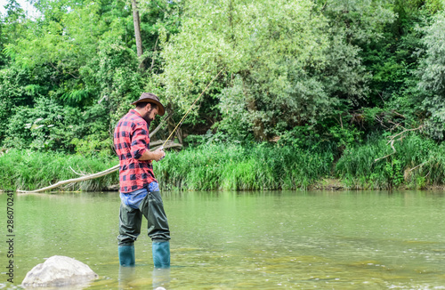 Fisherman alone stand in river water. Man bearded fisherman. Fisherman fishing equipment. Hobby sport activity. River lake lagoon pond. Trout farm. Fish farming pisciculture raising fish commercially