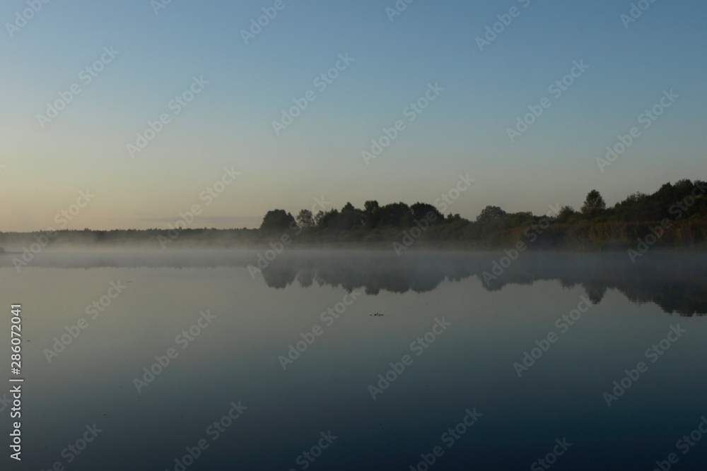 sunrise above a river on foggy summer morning, the sky reflections in the water,  misty reflection in steaming water, Salaca river, Latvia 