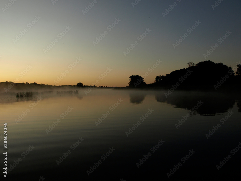 sunrise above a river on foggy summer morning, the sky reflections in the water,  misty reflection in steaming water, Salaca river, Latvia 