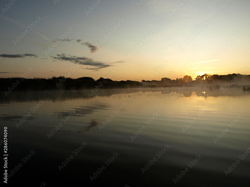 sunrise above a river on foggy summer morning, the sky reflections in the water,  misty reflection in steaming water, Salaca river, Latvia 