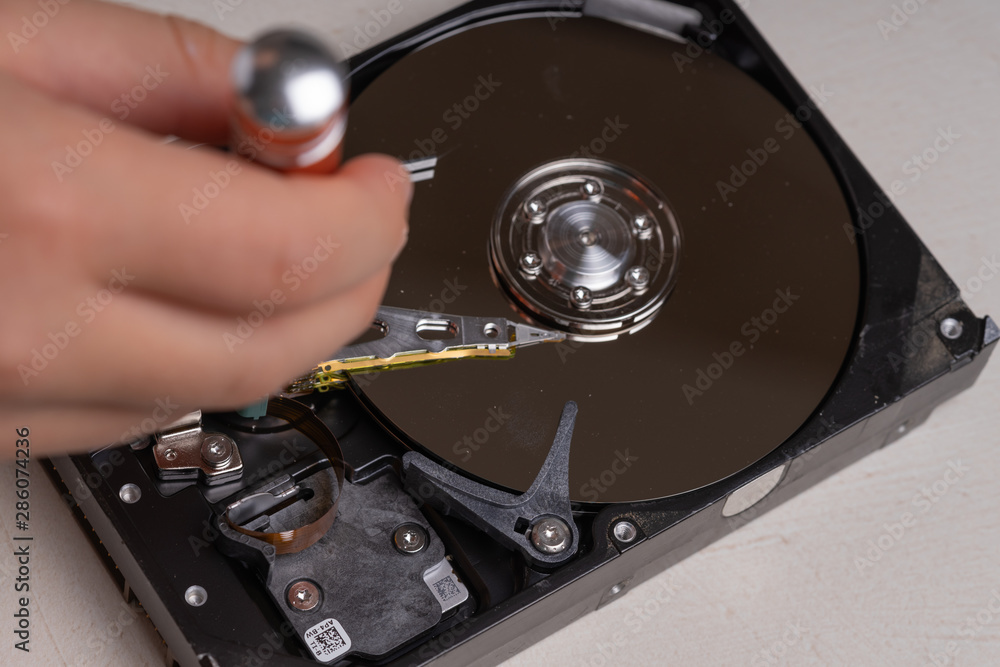 A teenager disassembles the hard drive of a computer to study its device. A teenager disassembles the hard drive of a computer to study its device.