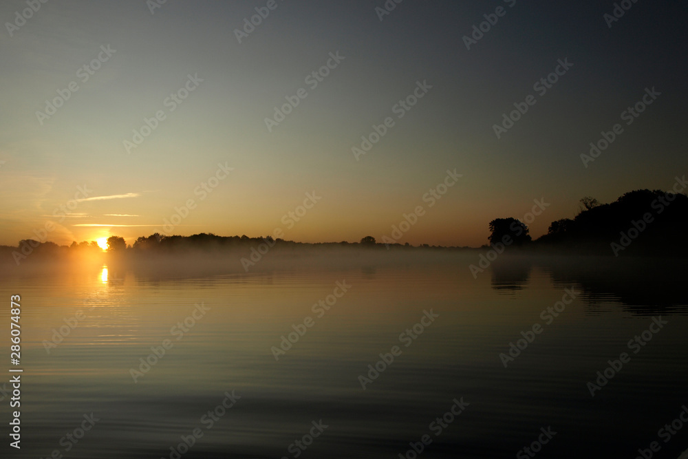 Obraz premium sunrise above a river on foggy summer morning, the sky reflections in the water, misty reflection in steaming water, Salaca river, Latvia 