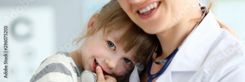 Paediatric doctor holding and hugging little cute girl patient portrait