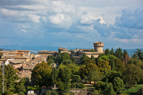 Cityscape of Volterra over the roofs with surrounding landscape, Medici fortress in background, Tuscany, Italy