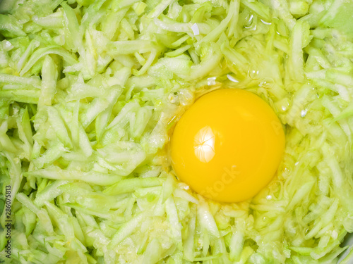 Cooking process: grated zucchini, egg. Raw materials for the preparation of vegetable waffles, pancakes. Food concept photo