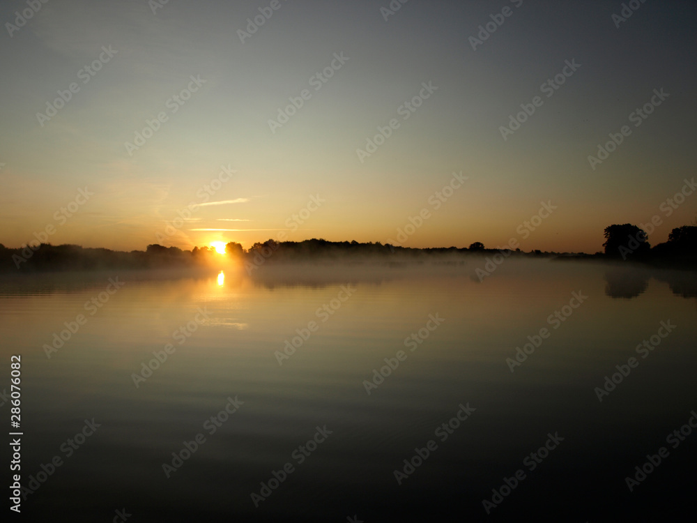 sunrise above a river on foggy summer morning, the sky reflections in the water,  misty reflection in steaming water, Salaca river, Latvia 