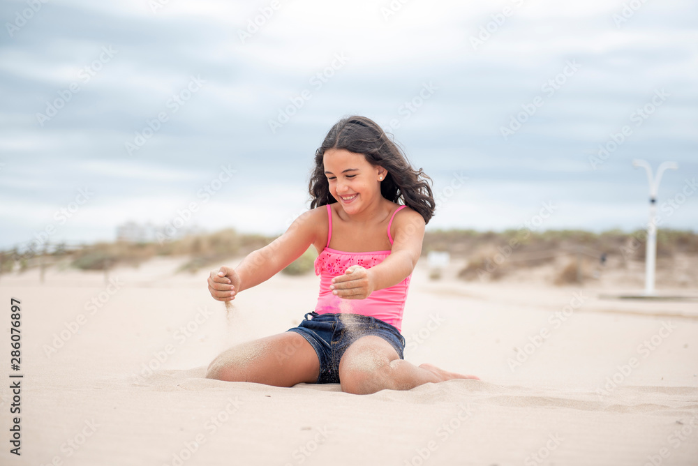 Pretty girl playing with the sand on the beach