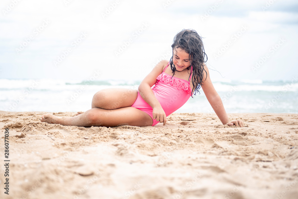 Pretty little girl playing with the sand on the beach Pretty little girl playing with the sand on the beach