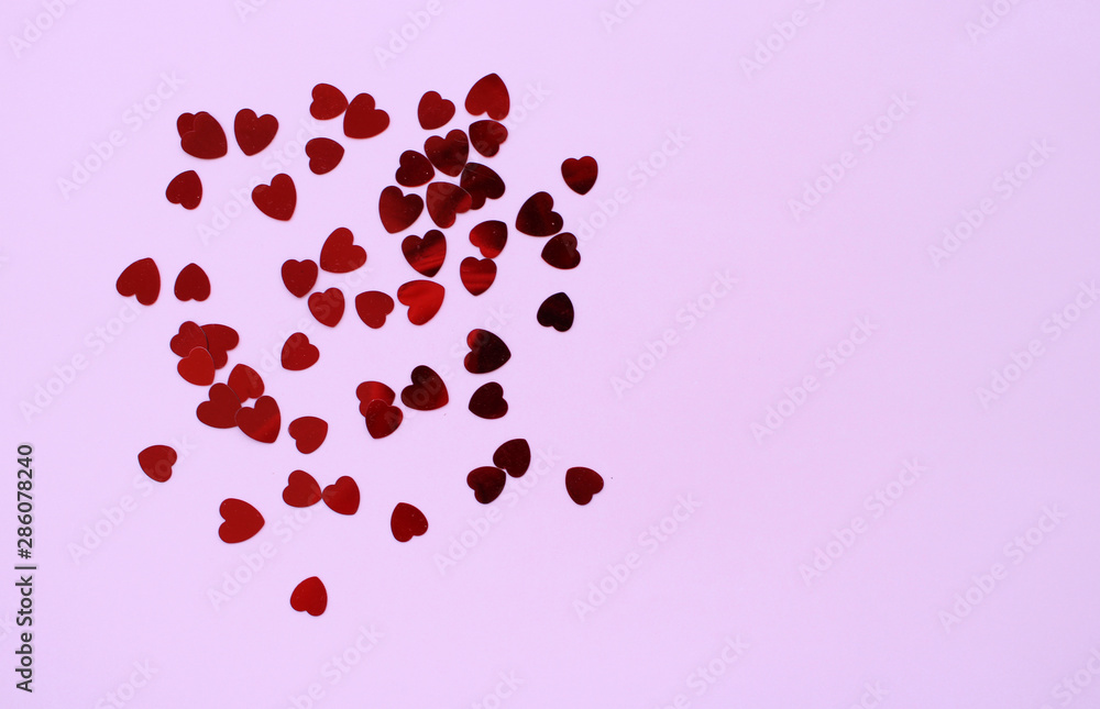Red hearts confeetti on a pastel pink background