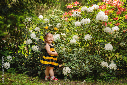 one year old child dressed up like a bee on blooming bush background photo