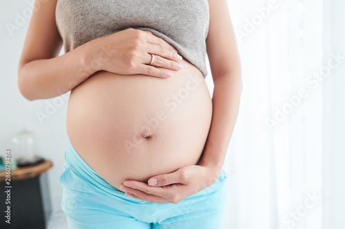 Cropped image of woman showing her big pregnant belly when anticiaping a baby © DragonImages