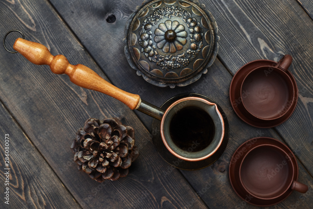 Coffee mockup with Traditional Turkish cezve and two empty clay cups on the old brown wooden table. Top view. Coffee mockup with Traditional Turkish cezve and two empty clay cups on the old brown wooden table. Top view.