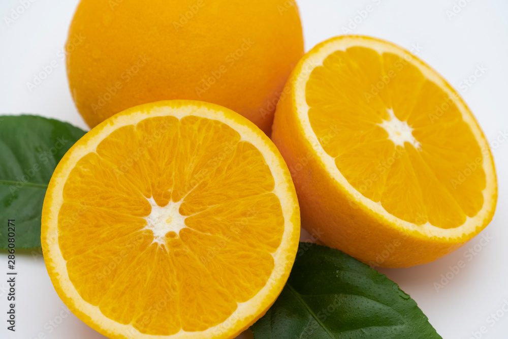 Fototapeta premium Half of orange and whole with green leaf isolated on white background