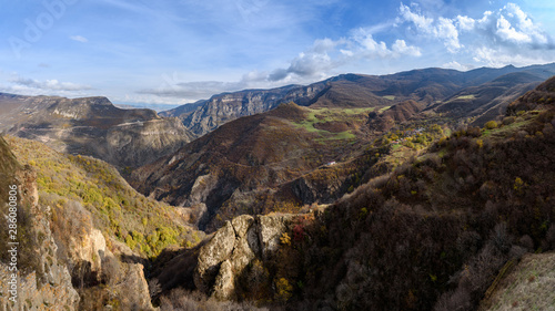 view of the mountain ranges on a bright sunny day with clouds in the sky and sun rays passing through the clouds  snow-covered tops of the mountain slopes on the horizon.