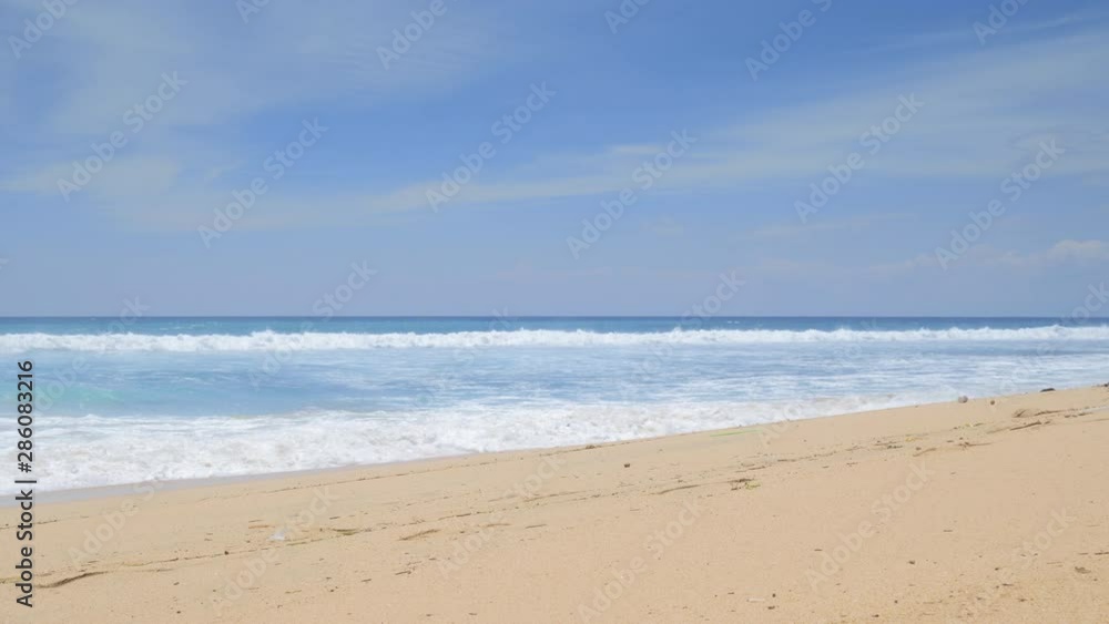 Tropical beach with high tide waves and splashes on sand with trails and plastic garbage Tropical beach with high tide waves and splashes on sand with trails and plastic garbage
