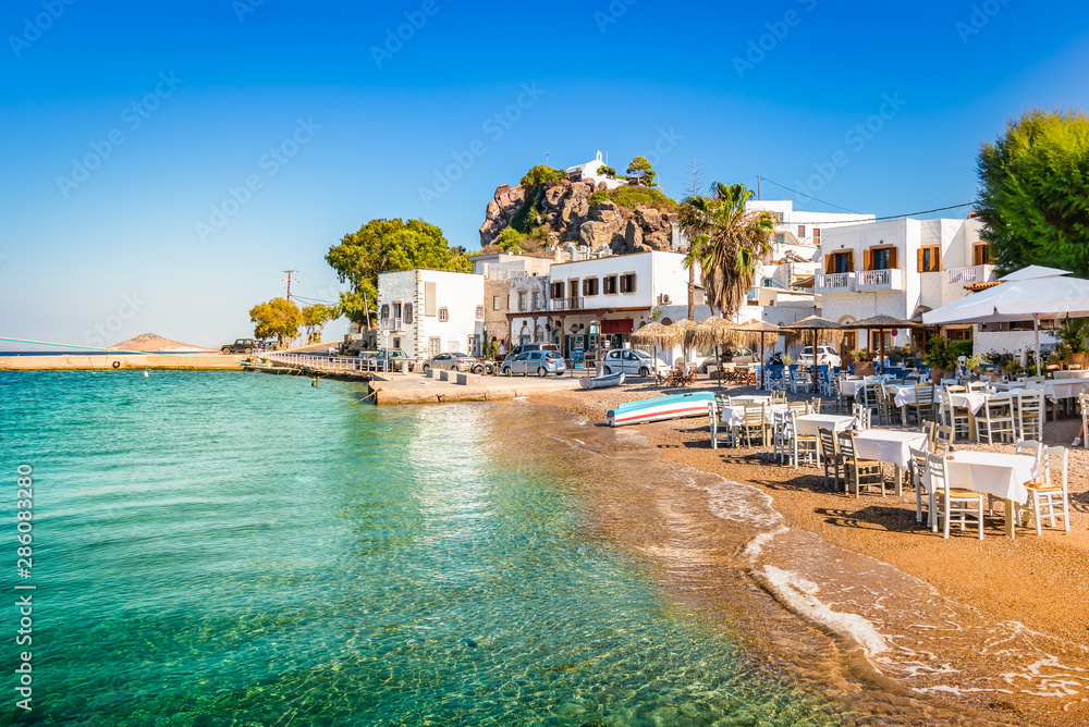 Patmos Island, Greece. Skala village and harbor view with beach at the port. - obrazy, fototapety, plakaty 