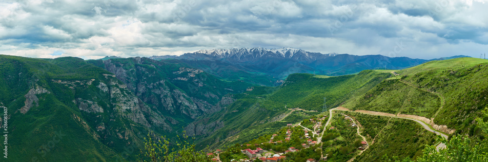 view of the village located in a mountain gorge on a bright sunny day with clouds in the sky.