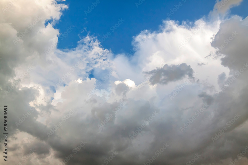 Cumulus clouds gather before the rain against a clear blue sky. Natural landscape.