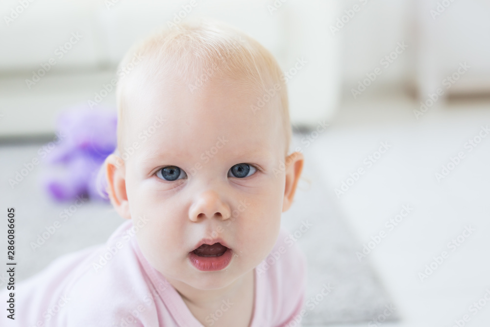 Children and childhood concept - Little baby girl sitting on the floor