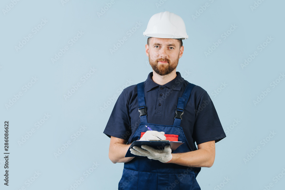 Construction engineer in a white helmet and blue uniform writing notes Construction engineer in a white helmet and blue uniform writing notes