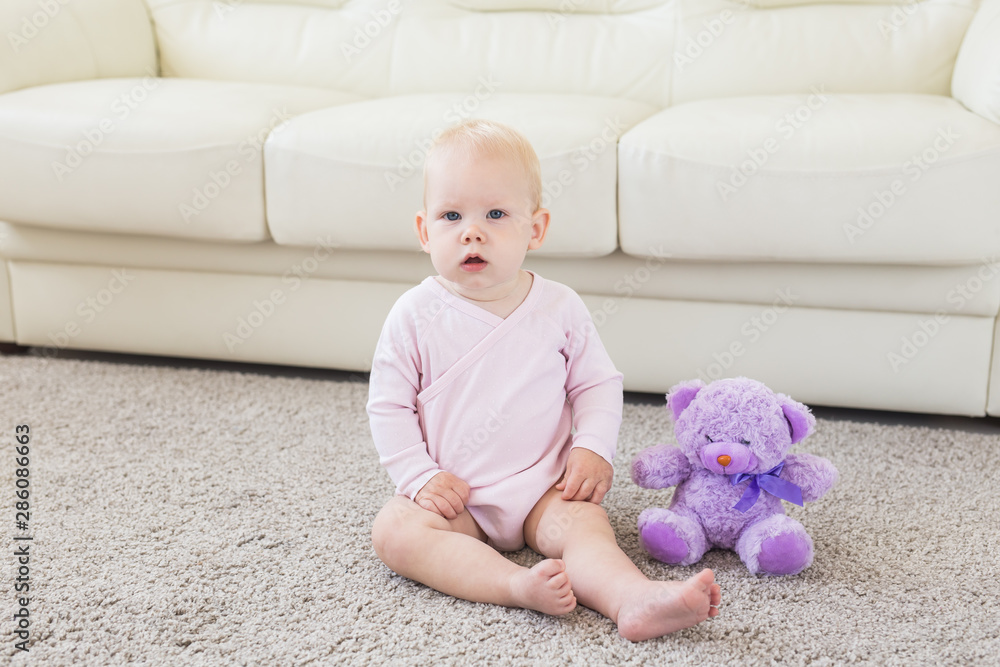 Childhood and children concept - Cute charming baby sitting on the floor Childhood and children concept - Cute charming baby sitting on the floor