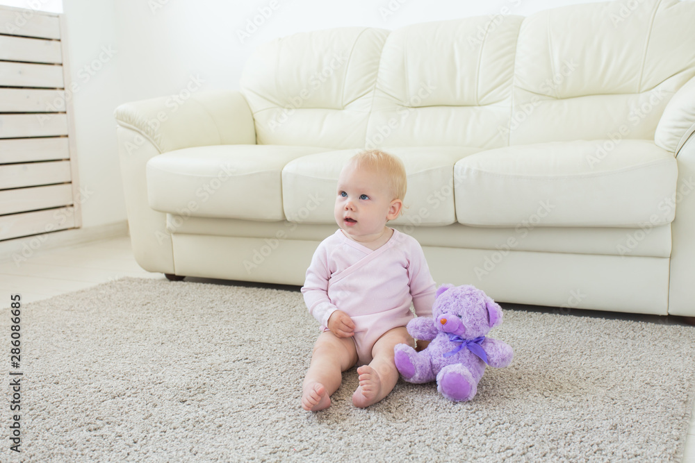 childhood, babyhood and children concept - happy little baby girl sitting on floor at home childhood, babyhood and children concept - happy little baby girl sitting on floor at home